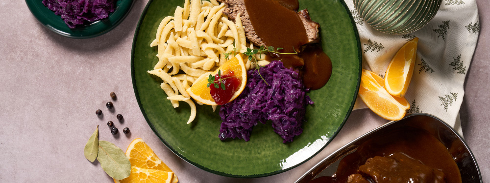 Sauerbraten mit Rotkraut und Nockerl angerichtete auf einem Teller