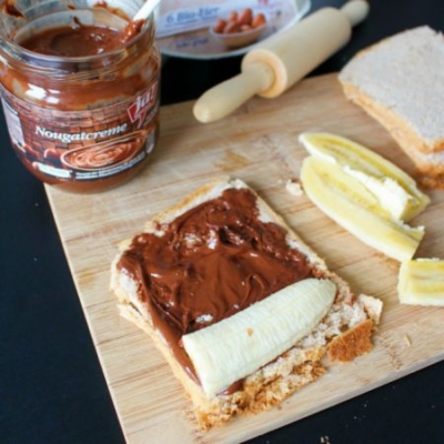 Ein Toastbrot mit Ja! Natürlich Bio-Nougatcreme mit einem Stück Banane daneben.
