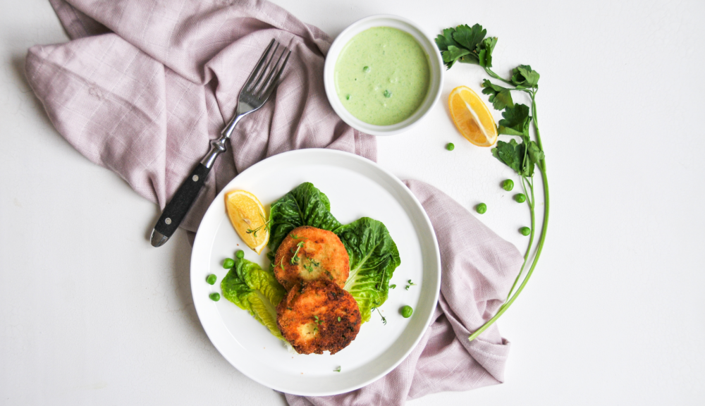 Kürbis-Kartoffel auf Teller angerichtet mit grünem Dip, Kräutern und Gabel