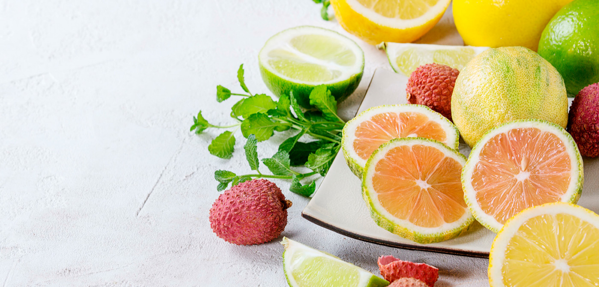 Zitronen aufgeschnitten auf einem Tisch mit Kräutern und Litchis