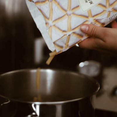 Jemand gibt Bio-Pasta in einen Topf.