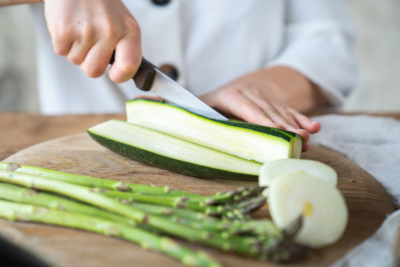 Jemand schneidet Bio-Zucchini.