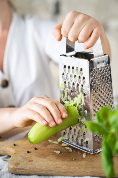 Jemand reibt eine Bio-Gurke.