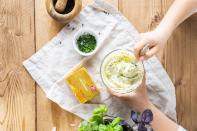 Jemand verrührt Kräuter mit schaumig geschlagener Bio-Butter.