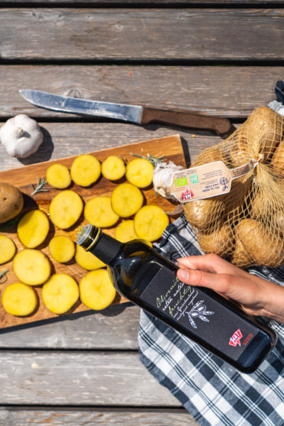 Jemand schüttet Ja! Natürlich Bio-Olivenöl über Kartoffelscheiben.