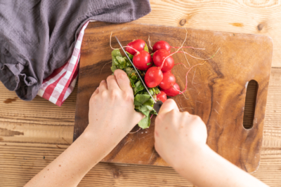 Jemand schneidet Bio-Radieschen.