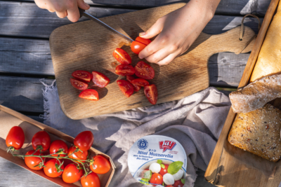 Jemand schneidet Bio-Paradeiser für den Ja! Natürlich Bio-Mini-Mozzarella.