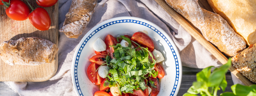 Eine Schüssel Bio-Mozzarella mit Paradeisern und Baguette.