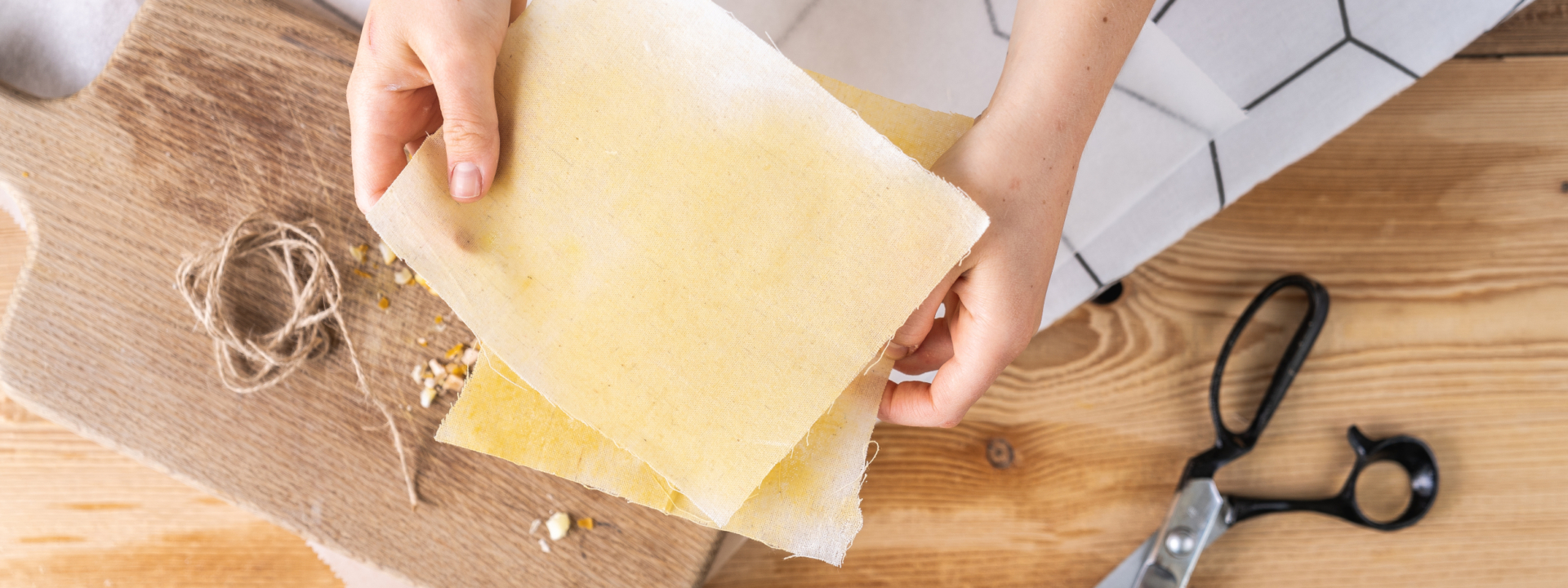 Jemand hält Bienenwachstücher, daneben eine Schere.