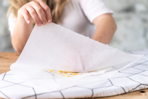 Jemand legt ein Backpapier über ein Backpapier mit Bienenwachs.