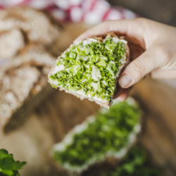 Jemand hält ein Schnittlauch-Salatbrot in der Hand.