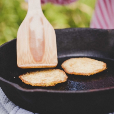 Jemand brät Hirse-Pancakes in einer Pfanne.