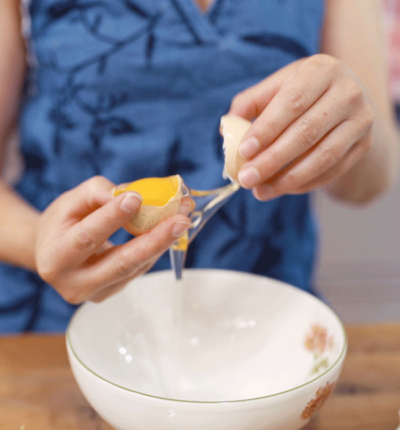 Jemand trennt Eiklar von Eigelb.