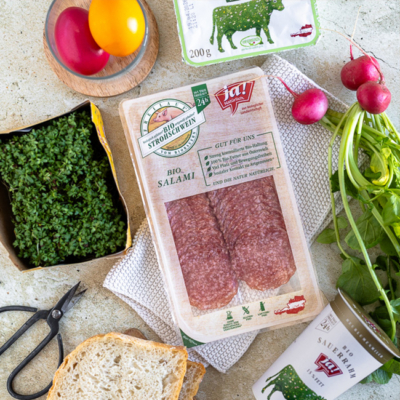 Bio-Salami, Bio-Kresse, Bio-Weißbrot, Bio-Sauerrahm und Bio-Ostereier auf einem Tisch