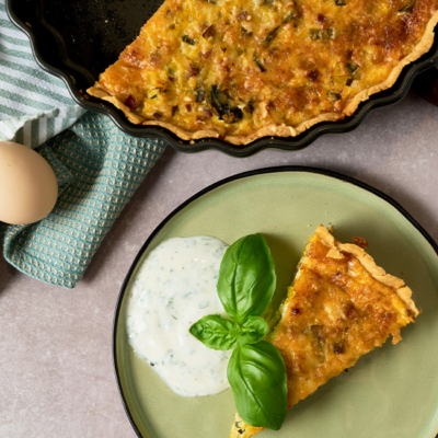 Quiche Lorraine in einer Backform und auf einem Teller serviert.