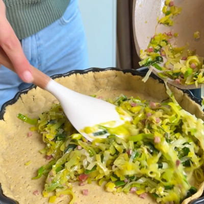 Lauch-Speck-Füllung wird auf dem fertigen Teig platziert.