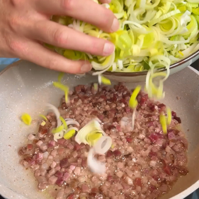 Speck und Lauch werden in einer Pfanne angebraten.