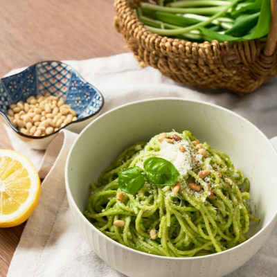 Bärlauch Pasta in einem Teller, garniert mit Pinienkernen und Basilikumblättern.
