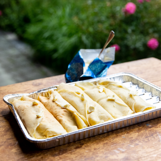 Ein Tablett mit Palatschinken steht auf einem Holztisch.