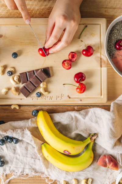 Jemand schneidet Bio-Kirschen, Schokolade und Bananen.