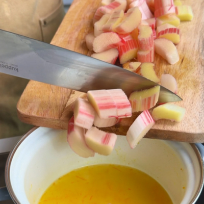Den geschnittenen Bio-Rhabarber mit Bio-Orangenzeste und Saft, Bio-Zucker und Wasser in einem Topf köcheln lassen.