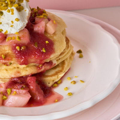 Gestapelte Pancakes getoppt mir warmen Bio-Rhabarber, der Reduktion, Bio-Pistazienkernen sowie Bio-Crème fraîche.