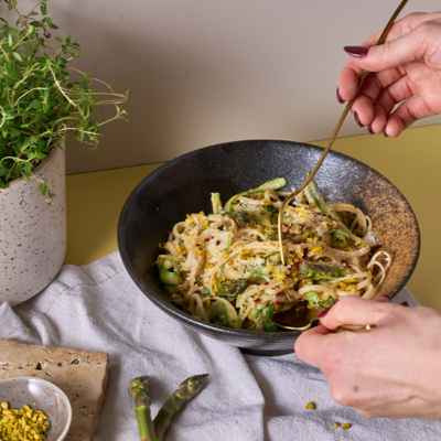 Spargel Zitronenbutter Pasta in einem Teller, getoppt mit Bio-Minze und Bio-Pistazien.