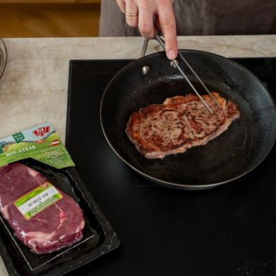 Bio-Weidejungrind Rib Eye Steak wird in einer Pfanne angebraten.