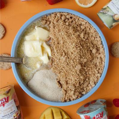 In einer Schüssel Bio-Frischkäse, zerdrückte Bio-Haferkekse, Bio-Butter und Bio-Rohrzucker vermengen.