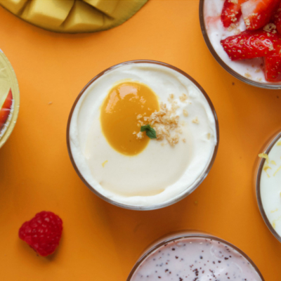 No-Bake Cheesecake angerichtet in einem Glas und garniert mit dem Ja! Natürlich Sommerfrisch Joghurts in der Sorte Tropical Dream.