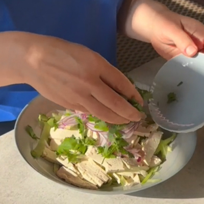 Bio-Koriander zu dem Räuchertofusalat hinzufügen.
