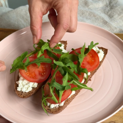 Bio-Brot mit Bio-Cottage Cheese , Bio-Rispentomaten und Bio-Rucola belegen.