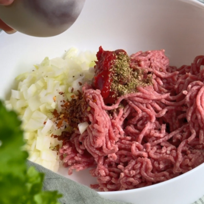 Bio Weidejungrind Faschiertes, Bio-Zwiebel und Gewürze in einer Schüssel.