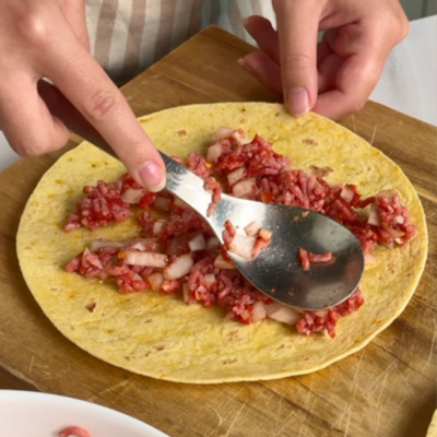 Lahmacun-Mischung wird auf Weizentortilla gestrichen.
