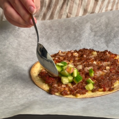 Bio-Gurken und Bio-Rispentomaten werden auf Lahmacun gelegt.