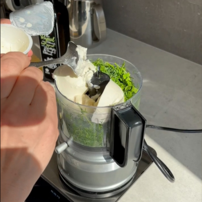 Mixer gefüllt mit Kräutern und Sauerrahm