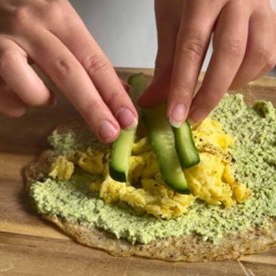Bio-Leinsamen-Oat-Wrap wird mit Rührei und Bio-Gemüse belegt.