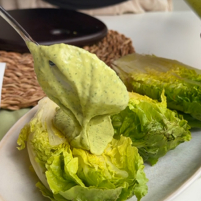 Das Bio-Caesar Dill Dressing wird auf die Salatherzen gegeben.