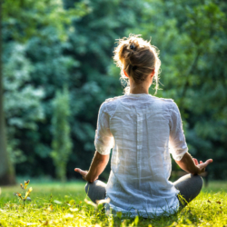 Frau macht im Park auf einer Wiese Yoga.