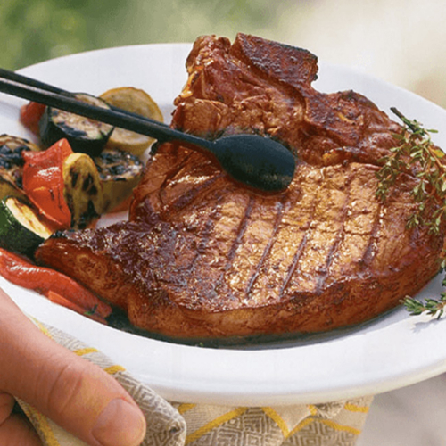 Frisch gegrilltes Ja! Natürlich Bio-Steak vom Weidejungrind auf einem Teller mit gerilltem Bio-Gemüse.