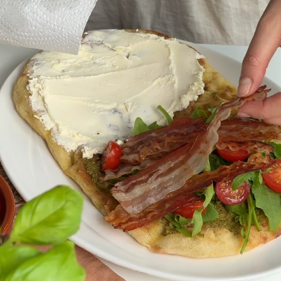 Focaccia mit Bio-Rucola, Bio-Tomaten und gegrilltem Bio-Bauchspeck vom Freilandschwein belegen.