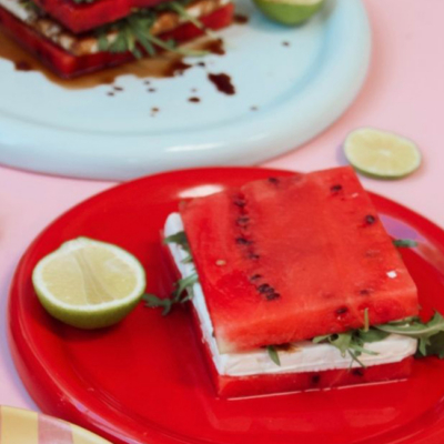 Das fertige Bio-Wassermelonen-Feta-Sandwich liegt auf einem Teller, daneben eine halbierte Bio-Limette.