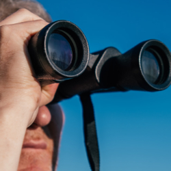 Mann mit Fernglas schaut in die Weite