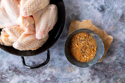 Rohes Bio-Hühnerfleisch und Gewürzmischung in einer Schüssel.