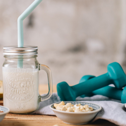 Selbstgemachter Bio-Proteinshake mit Bio Skyr, neben Hanteln.