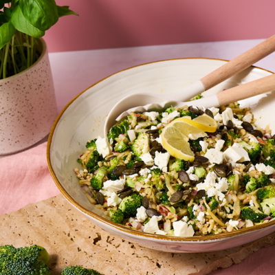 Der Brokkoli-Apfel-Salat, getoppt mit Bio-Kürbiskernen und Bio-Feta ist in einer Schüssel serviert.