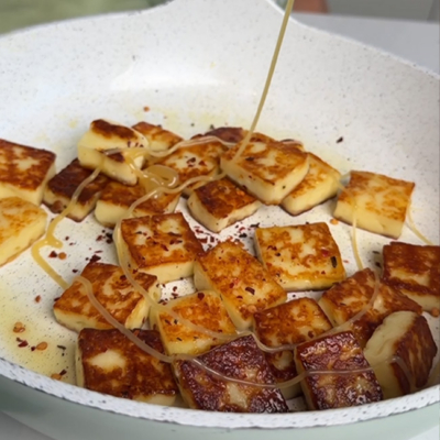 Der Bio-Halloumi wird in einer Pfanne goldbraun gebraten und anschließend wir Bio-Waldhonig sowie Chiliflocken hinzugegeben.