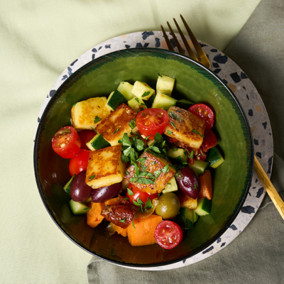 Der Süßkartoffel-Halloumi Salat getoppt mit frischer Bio-Petersilie wird in einer Schüssel serviert.