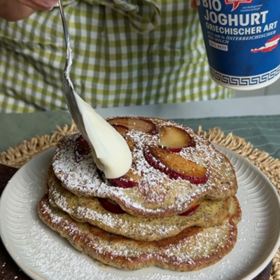 Die fertigen Zwetschken Pancakes mit Staubzucker und Bio-Joghurt griechischer Art toppen.
