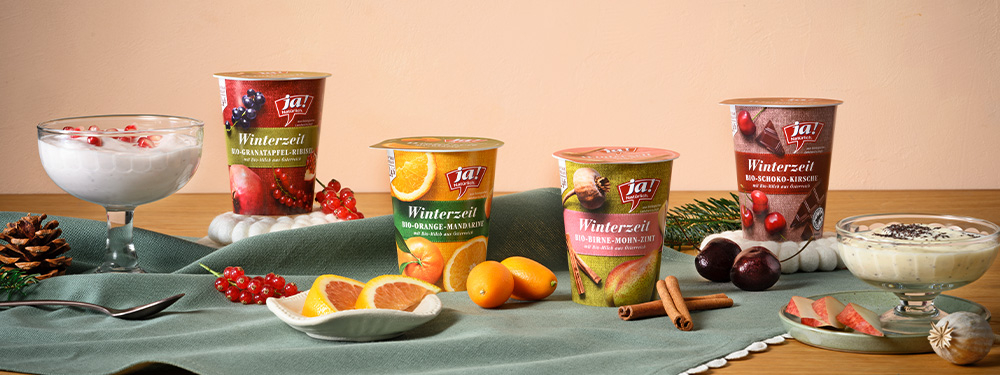 Winterzeitjoghurts aufgereiht mit frischen Früchten und Joghurt im Glas auf einem Tisch